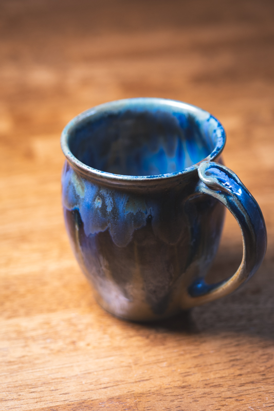 A mug with a pulled handle, glazed in flowing cobalt blue over violet and brown.