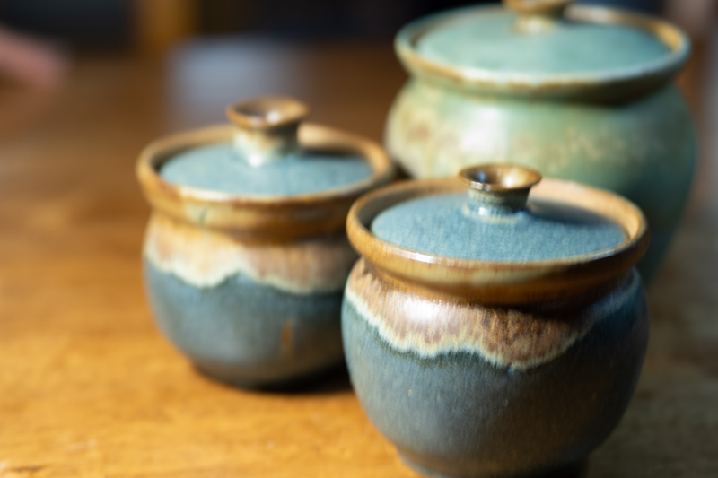 Three lidded jars of different sizes grouped together, in indigo and pale celadon.