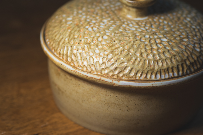 Close detail of a hand-carved casserole lid, each mark cut individually into the clay.