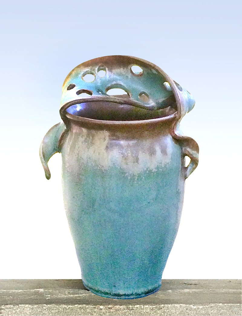 A tall verdigris vessel with a pierced lid folded over the rim and two small lug handles.